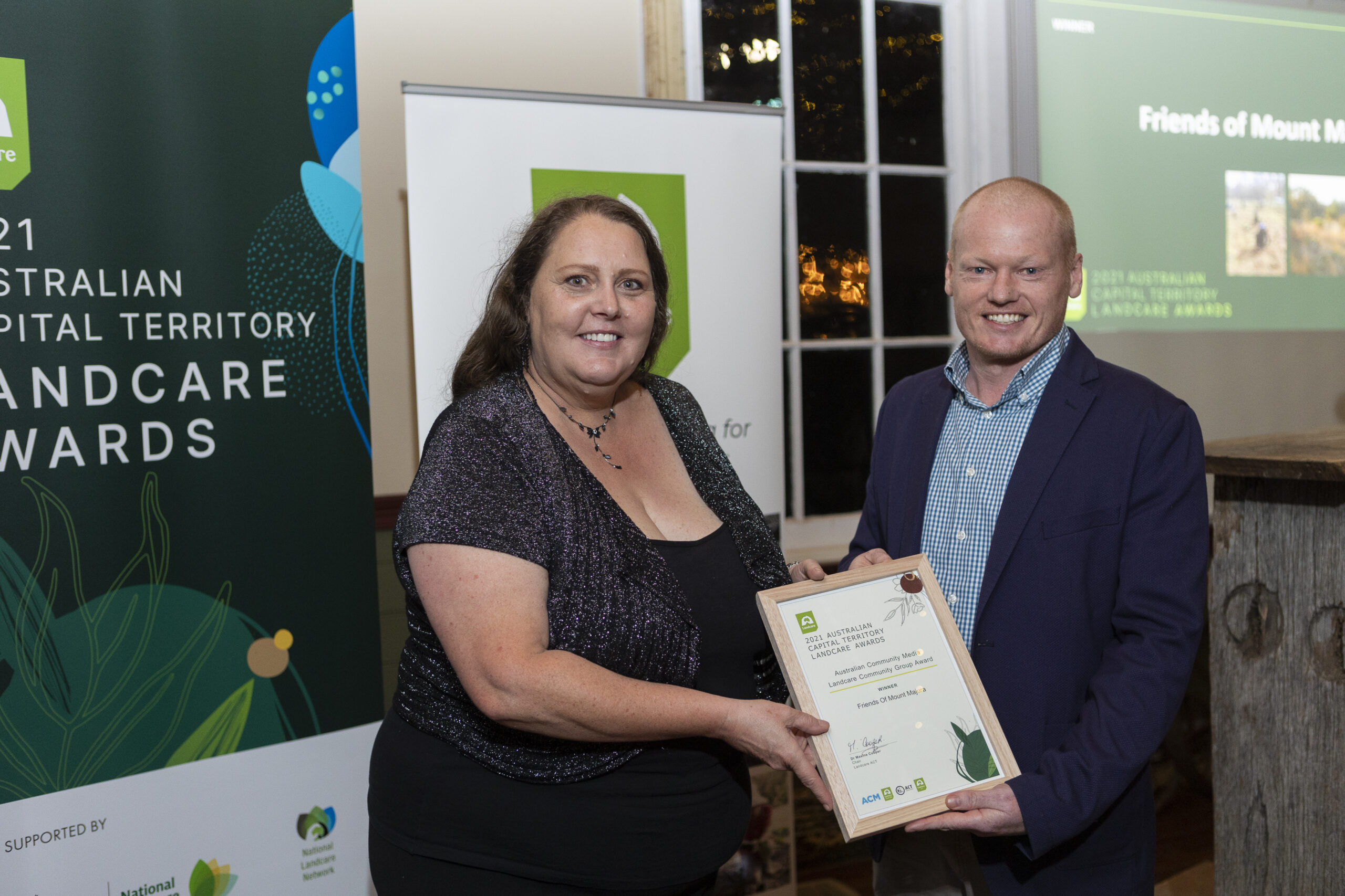 Photo of woman and man holding an award