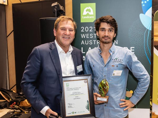 Photo of two men, one holding award
